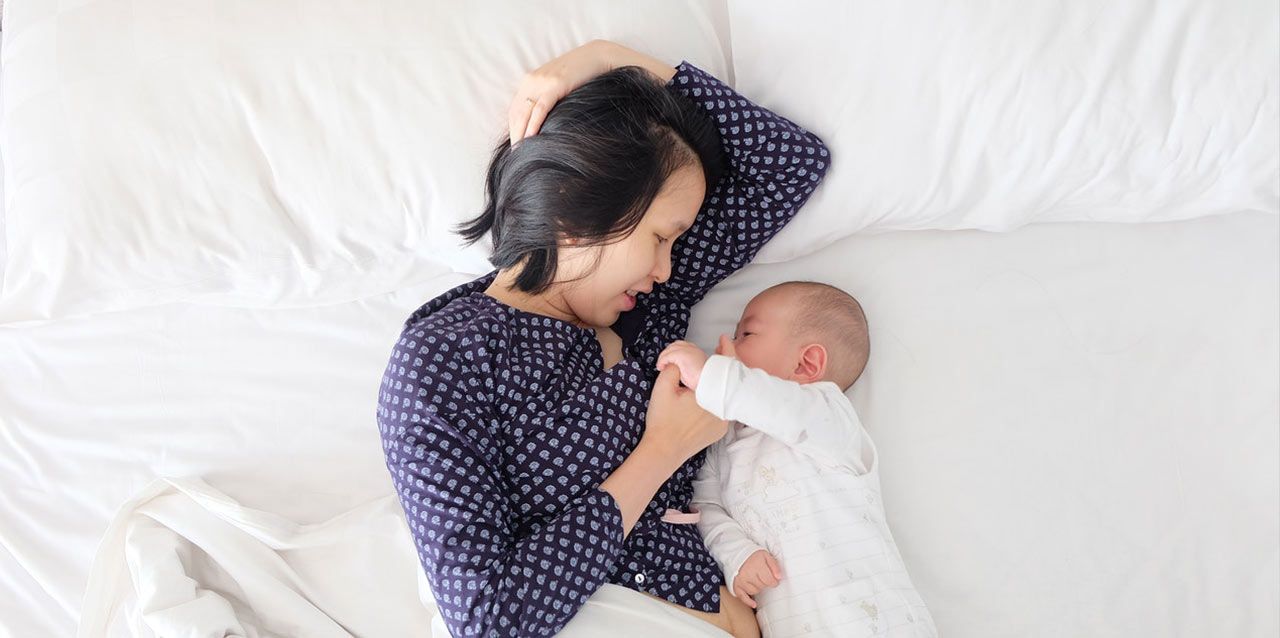 Consejos para colecho madre jugando con bebé en colchón