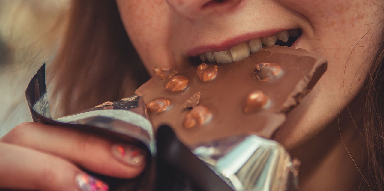 niña mordiendo tableta de chocolate con avellanas