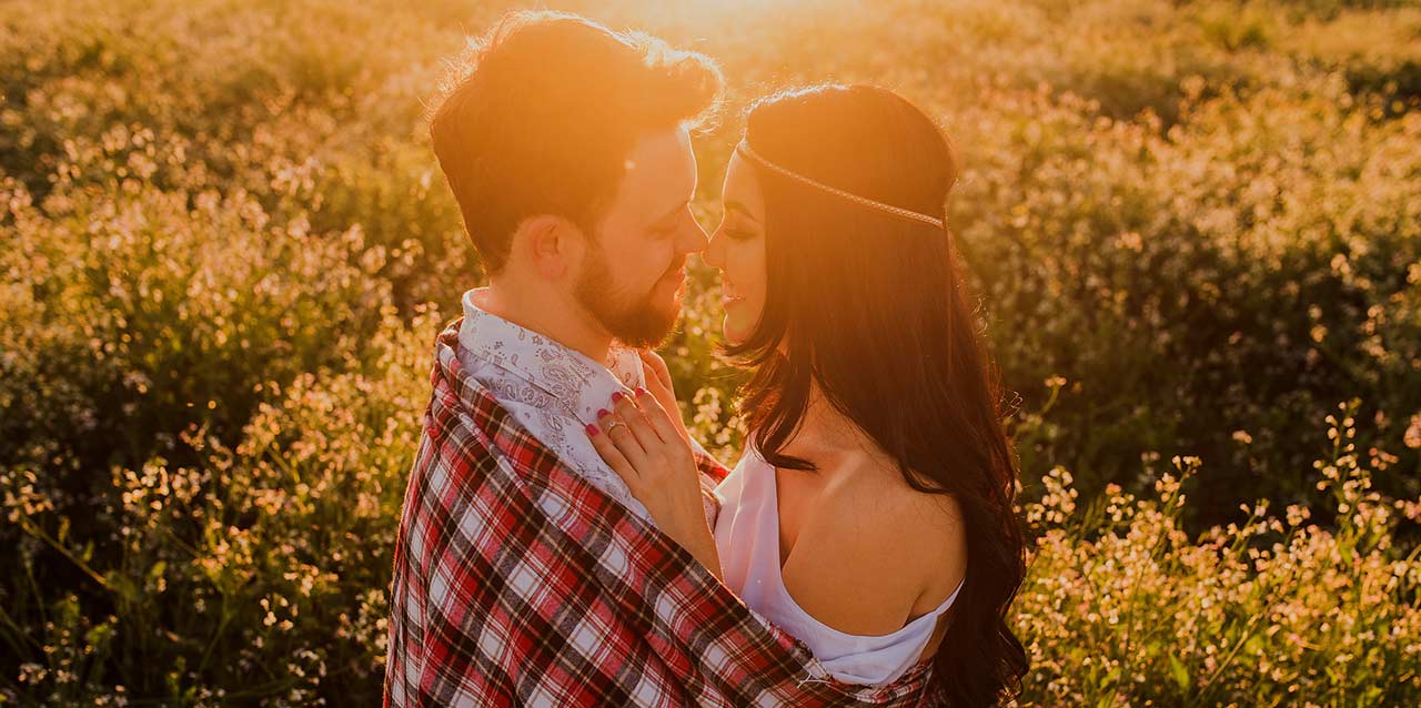 Pareja besándose en prado con flores