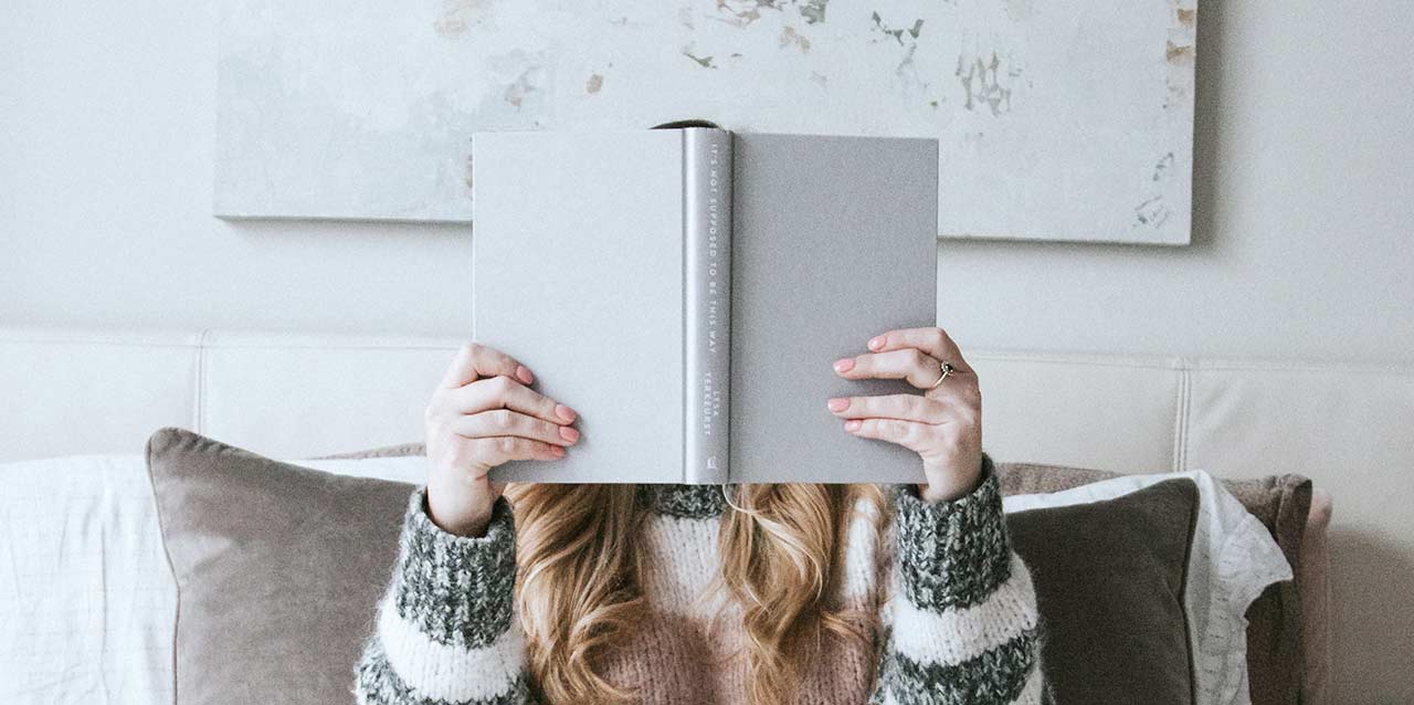 chica tapando su cara con libro