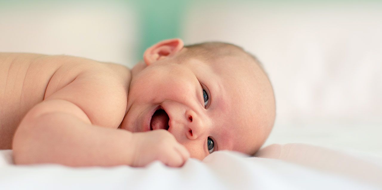 bebé tumbado de lado sonriendo