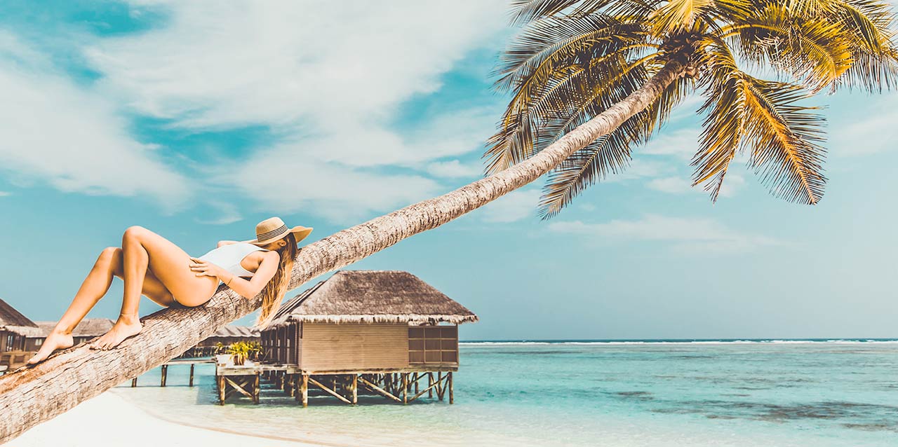 mujer tumbada en palmera junto a playa