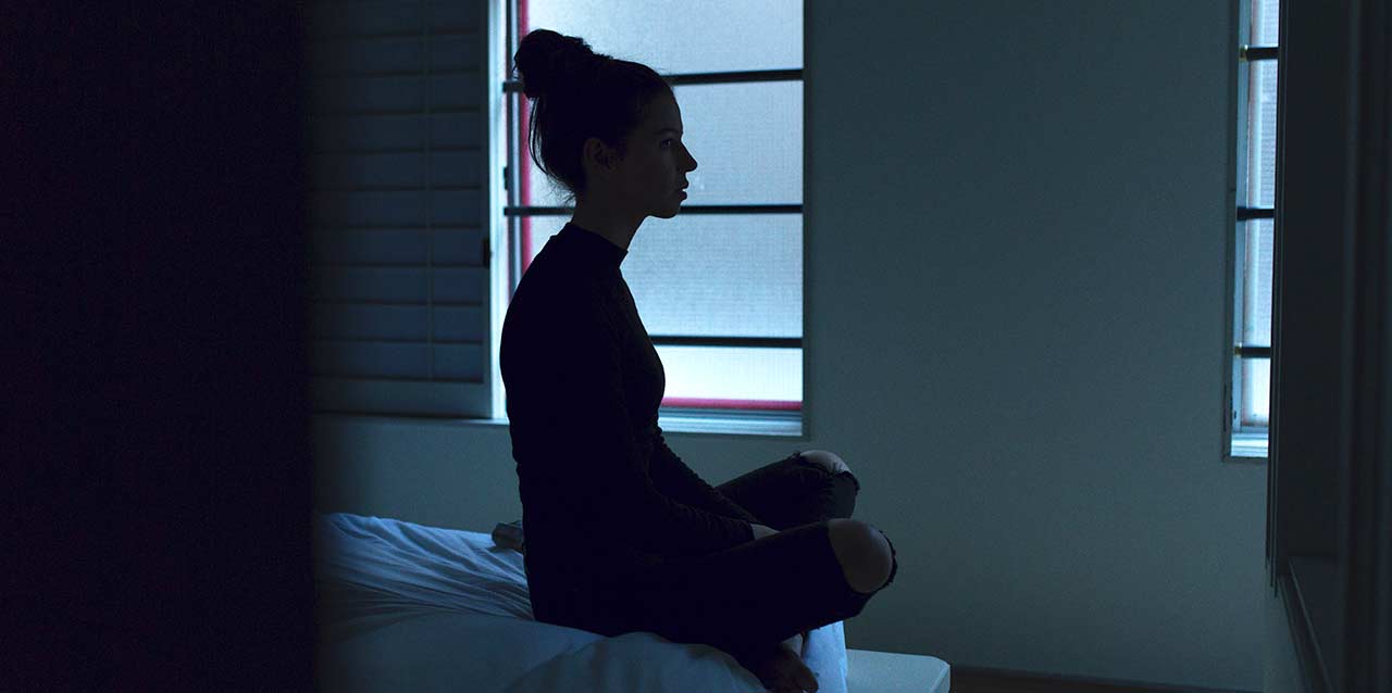 mujer con insomnio sentada en borde de cama