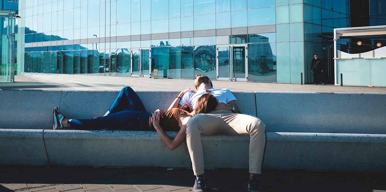 pareja durmiendo en banco de piedra