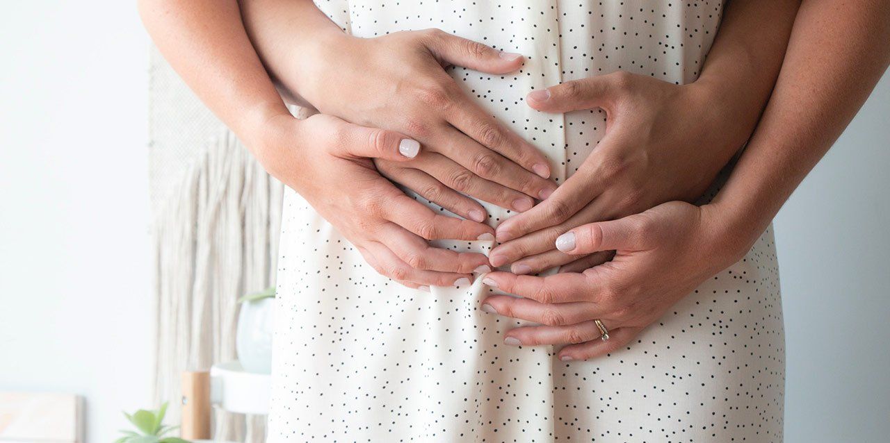 cuatro manos sobre barriga de embarazada