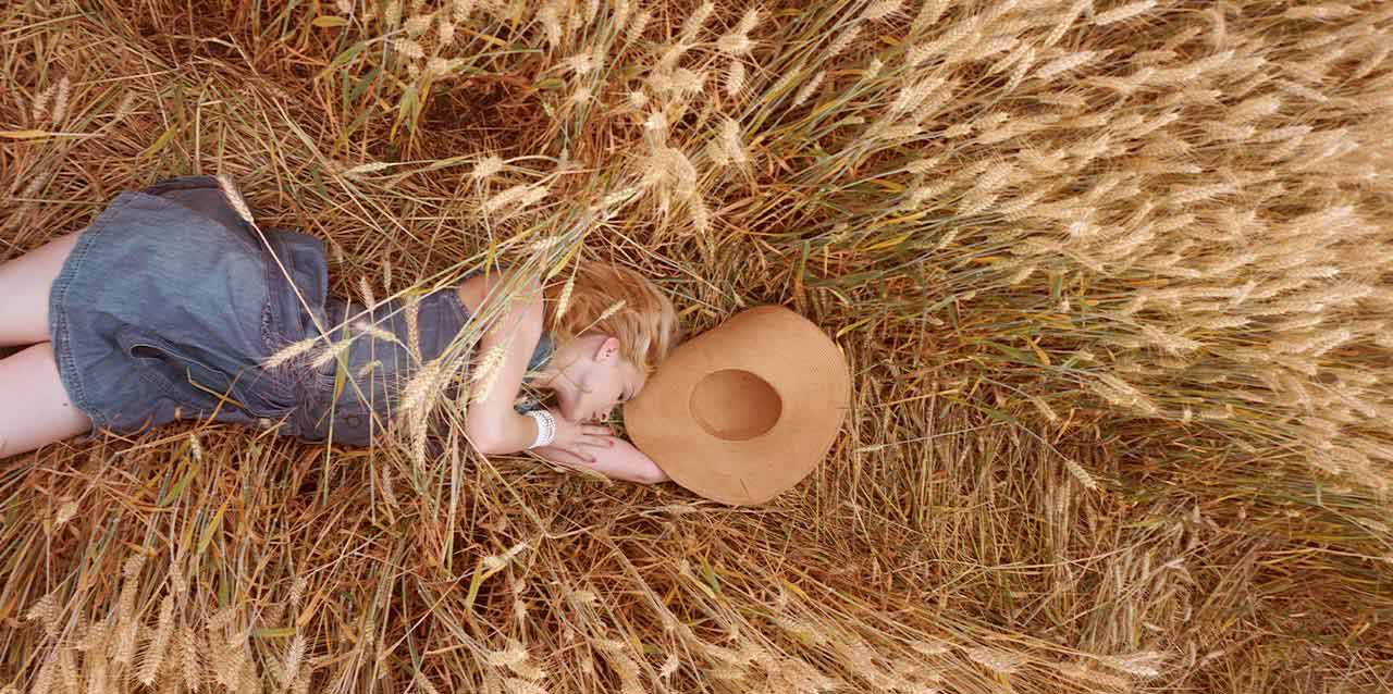 mujer con vestido vaquero tumbada en campo de trigo