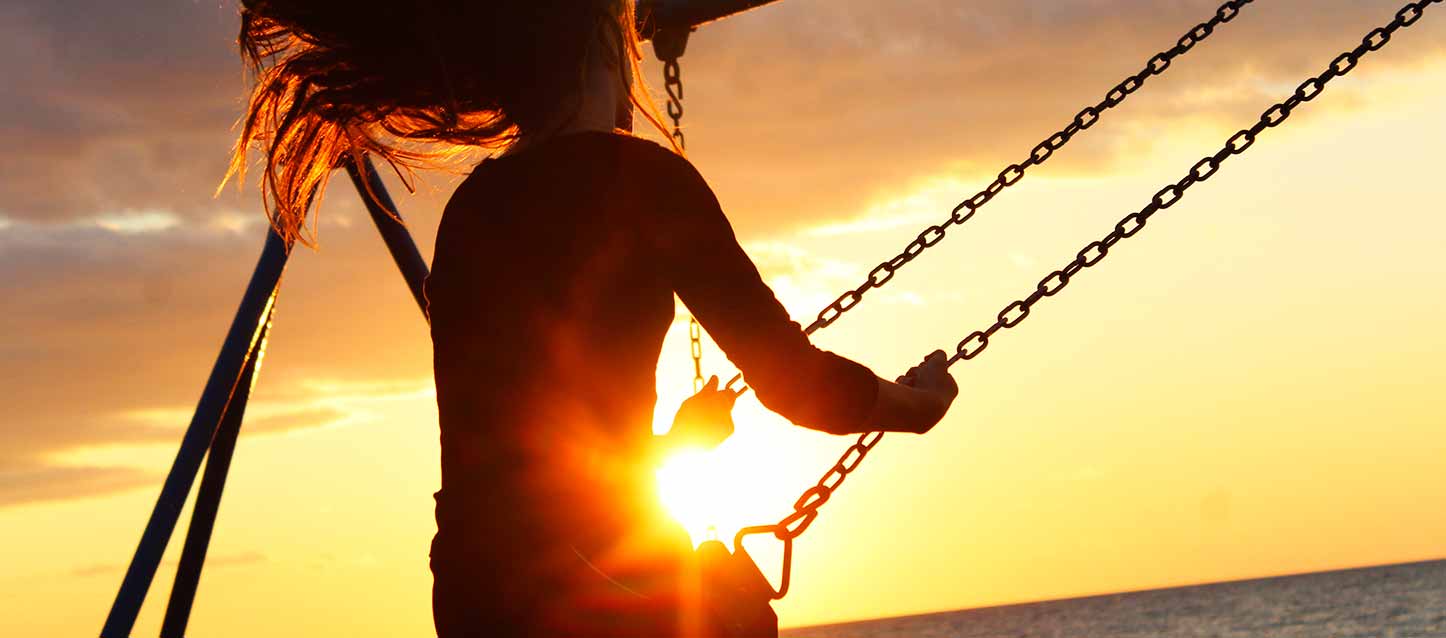 niña columpiándose en atardecer