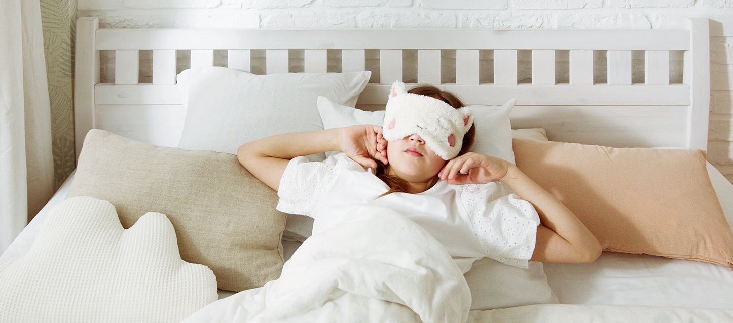 chica de pelo castaño con antifaz con forma de oveja durmiendo boca arriba tapada con edredon blanco soñando que no puede gritar en sueños