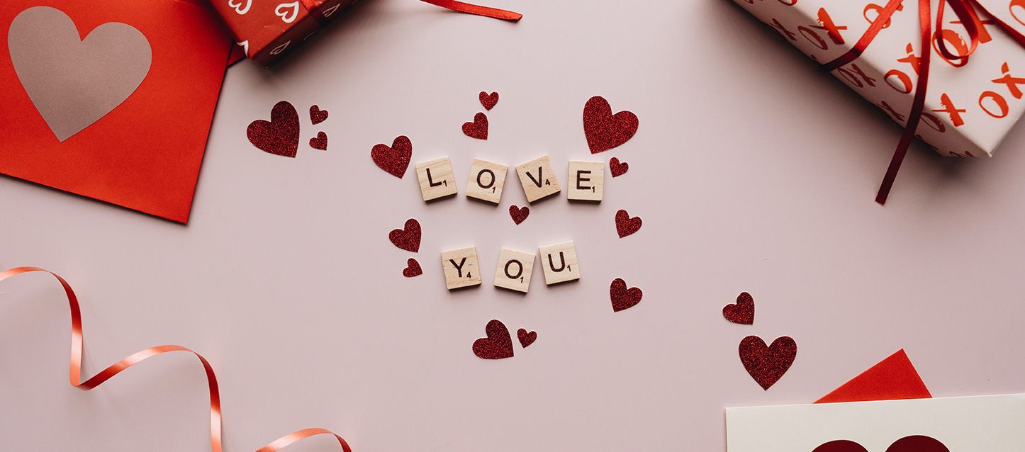fichas de scrabble formado la palabra Love You sobre la mesa y corazones de decoración alrededor