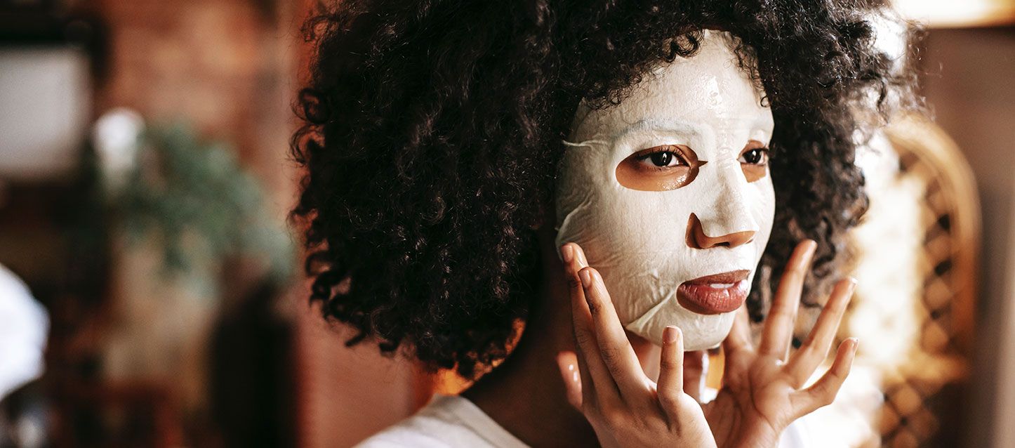 chica morena de pelo rizado con mascarilla facial