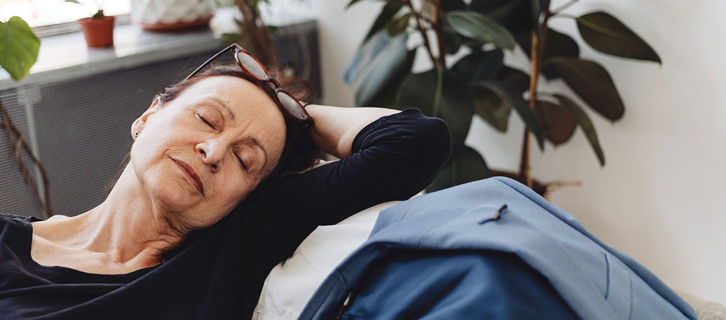 mujer con gafas en el pelo con jersei negro durmiendo en un sofá