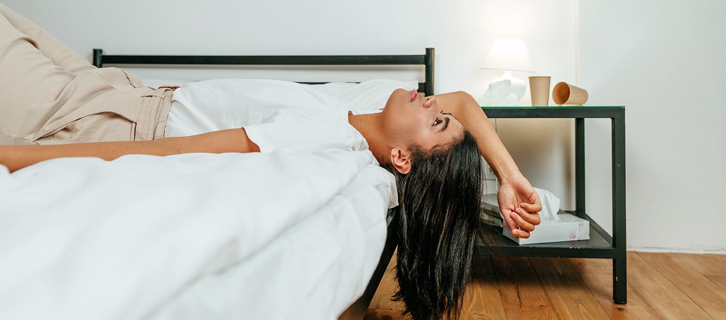 chica morena de pelo largo tumbada boca arriba en la cama mirando al techo