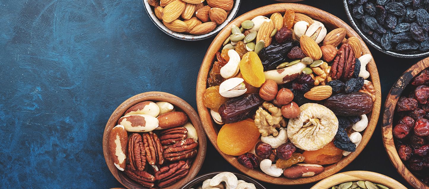 varios boles con frutos secos y frutas deshidratadas como anacardlos, nueces, orejones, datiles, pipas de calabaza y coquitos