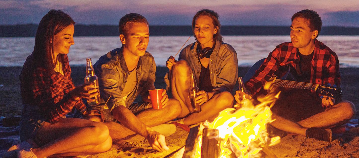 amigos sentados en la arena en la Noche de San Juan rituales y secretos