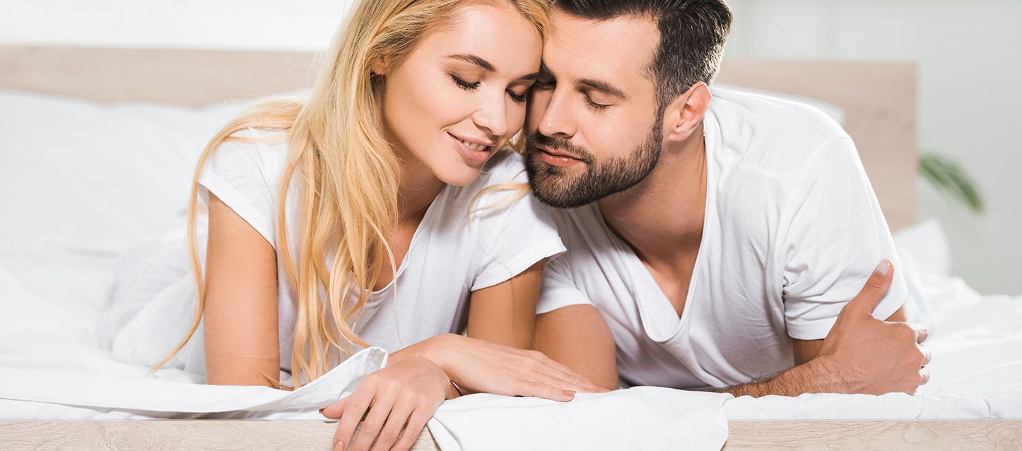 pareja tumbada abajo en la cama en actitud cariñosa