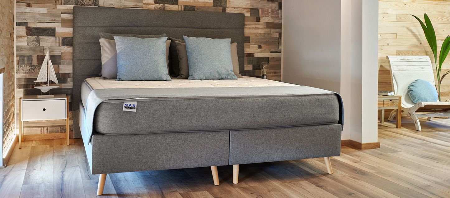 canapés abatibles, colchon con cojines y almohadas encima, cabecero gris y mesita con velero decorativo encima
