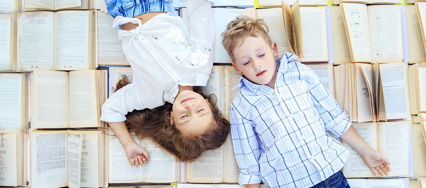 un niño y una niña durmiendo sobre libros