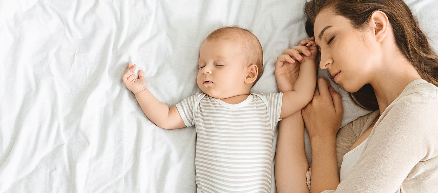 madre durmiendo junto a su bebe en la cama