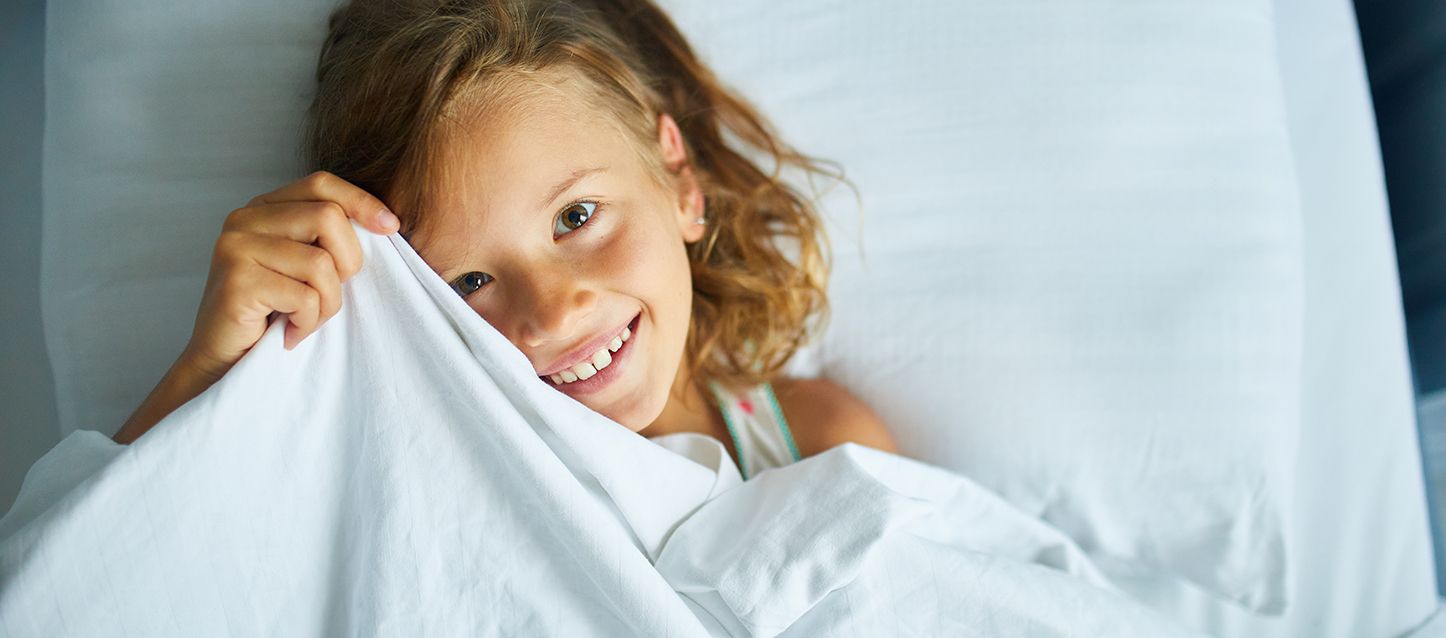 niña sonriente tapada con una sábana