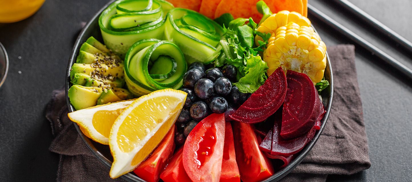 Ensalada en un bol con tomate, remolacha, maiz, calabacin, limon, calabaza y arandanos