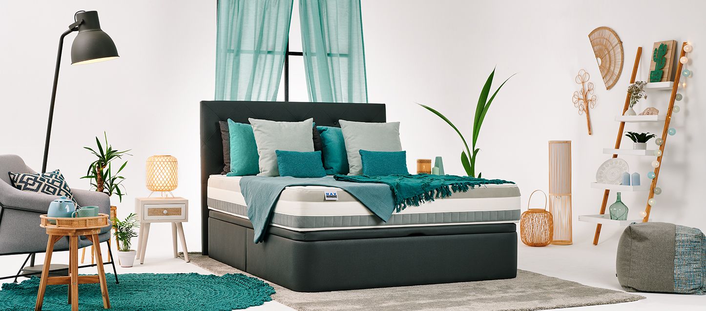 Habitación con soporte con colchón firme y cabecero, mesita de noche, sillónm puf, estanteria con objetos y ventana con cortina